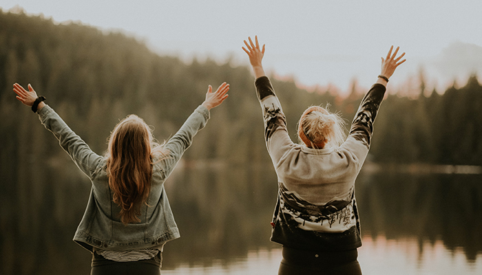 Deux femmes levant les bras devant un lac